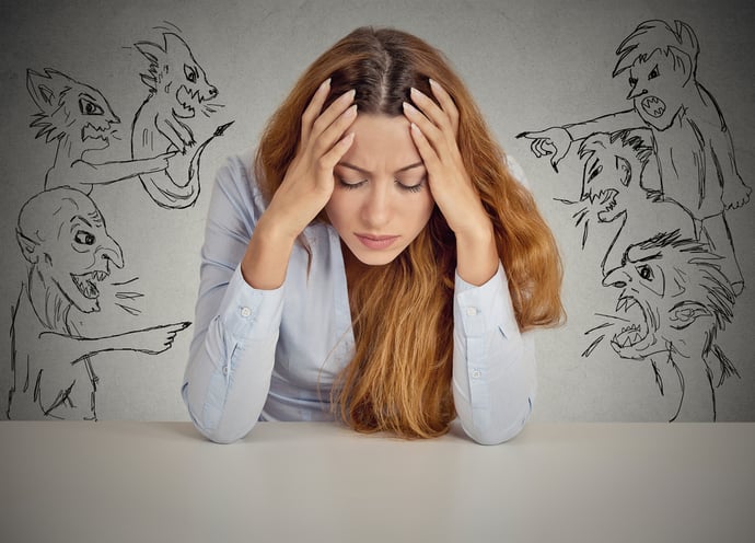 Evil Men pointing at stressed woman. Desperate young businesswoman sitting at desk in her office isolated on grey wall background. Negative human emotions face expression feelings life perception