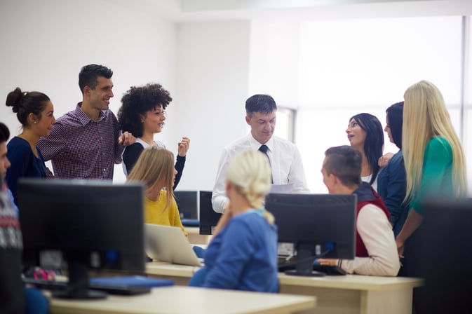group of students with teacher in computer lab classrom learrning lessons, get help and support-1